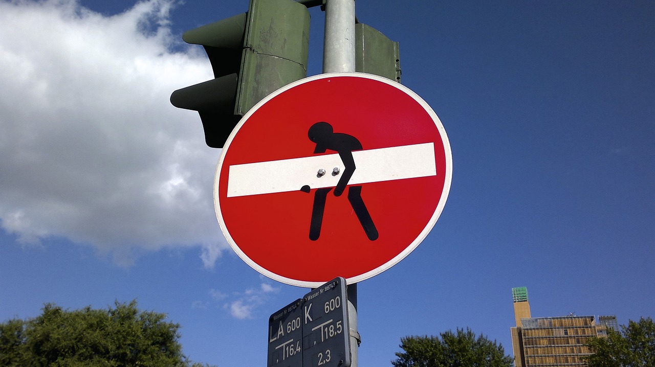 a red and white street sign sitting next to a traffic light, a photo, by Jan Rustem, street art, men, screw, ouch, stick poke