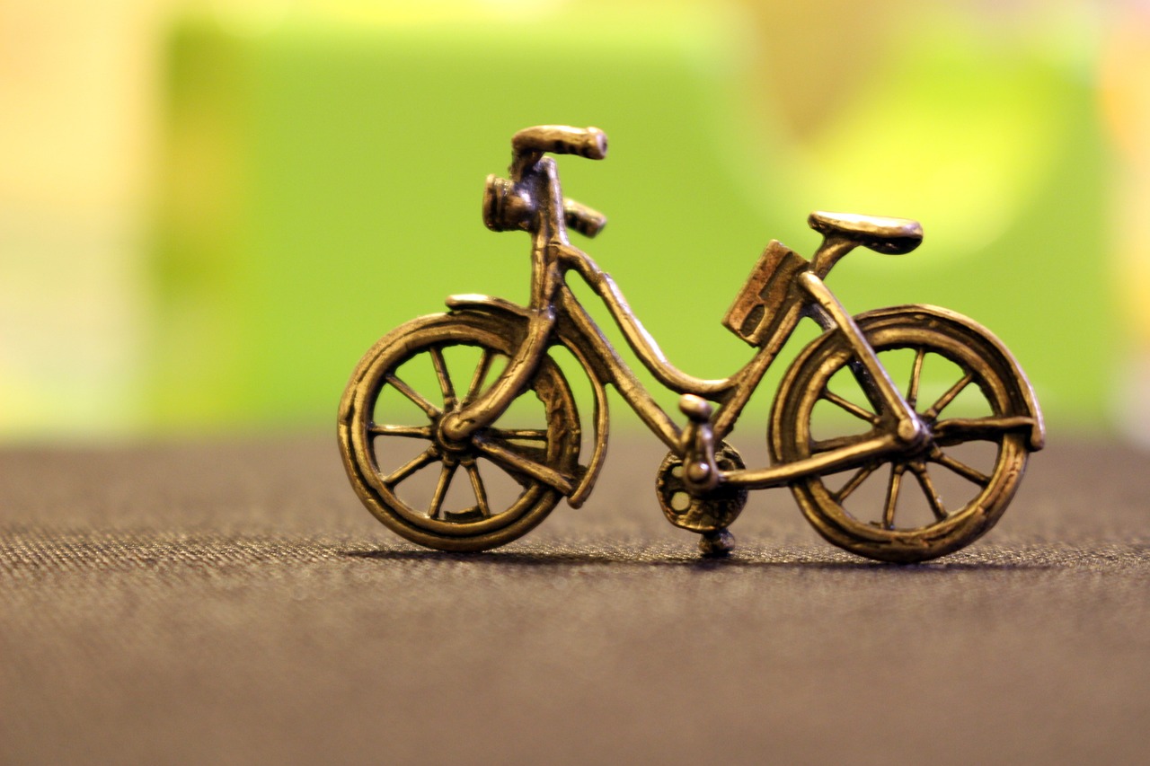 a toy bike sitting on top of a table, unsplash, close up shot of an amulet, made of bronze, miniature product photo, closeup - view