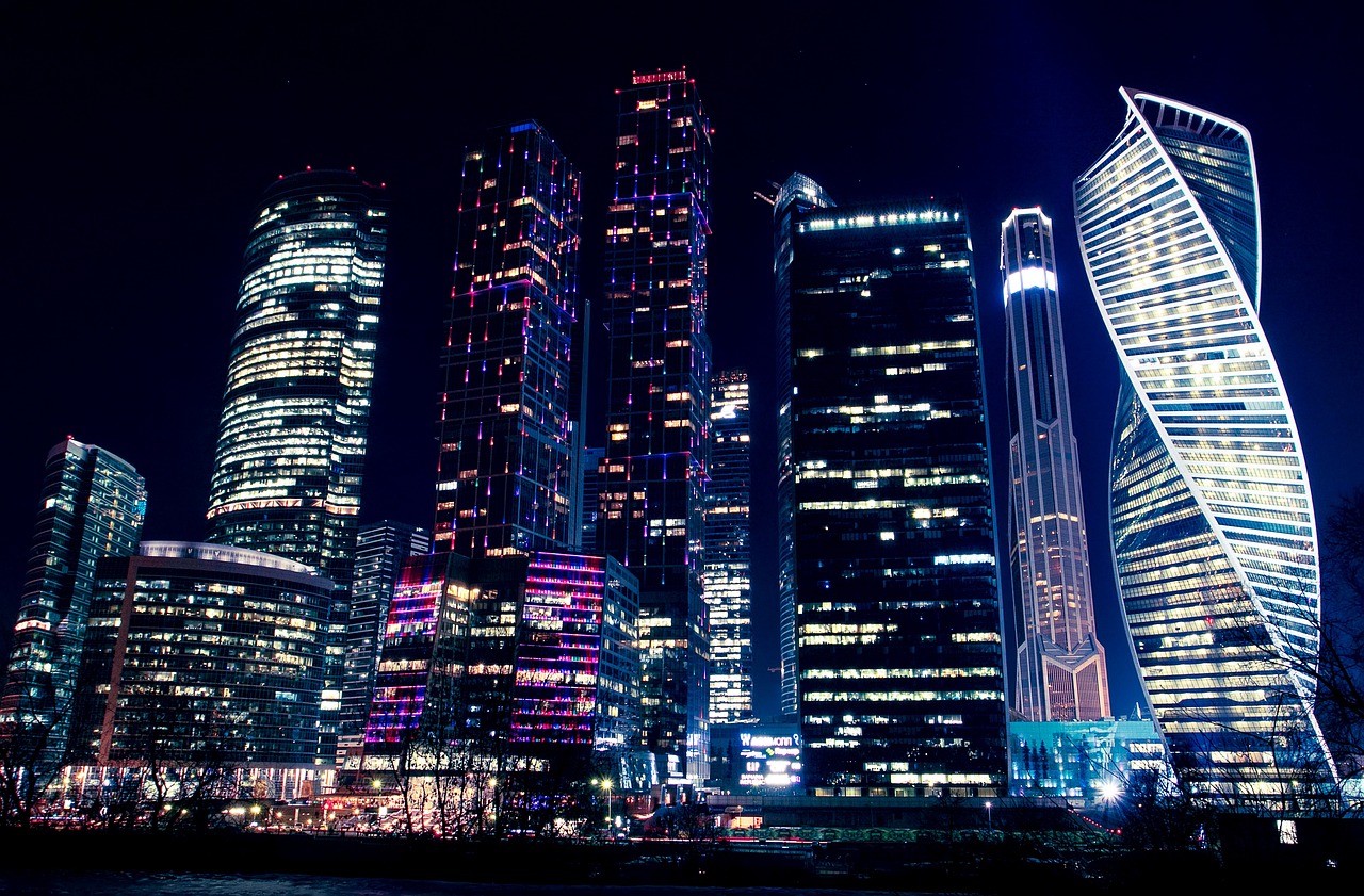 a group of tall buildings lit up at night, a stock photo, by Andrei Kolkoutine, pexels, hypermodernism, city of the future in russia, night time footage, asia, sanctions in russia