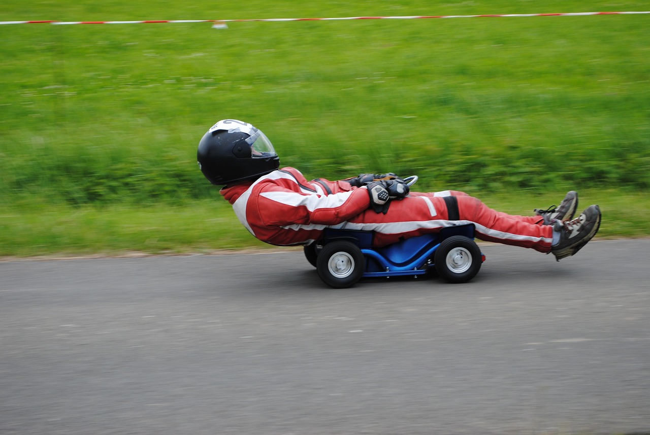 a man riding on the back of a cart down a road, flickr, happening, crazy racer spinning, cad design of lawnmower, hev suit, in a race competition