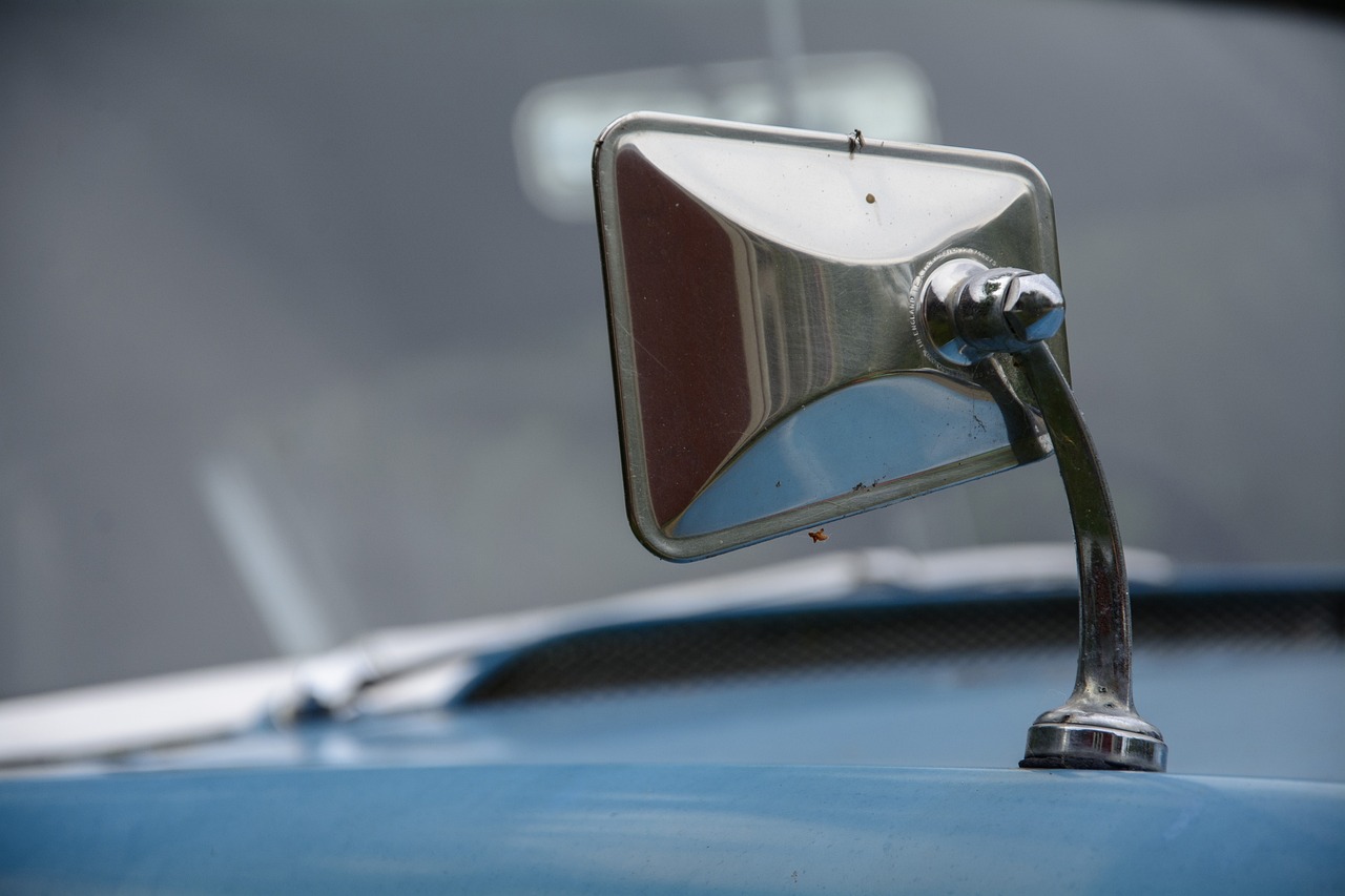 a close up of a mirror on a car, by Edward Corbett, classic car, sky blue, caravan, telephoto shot