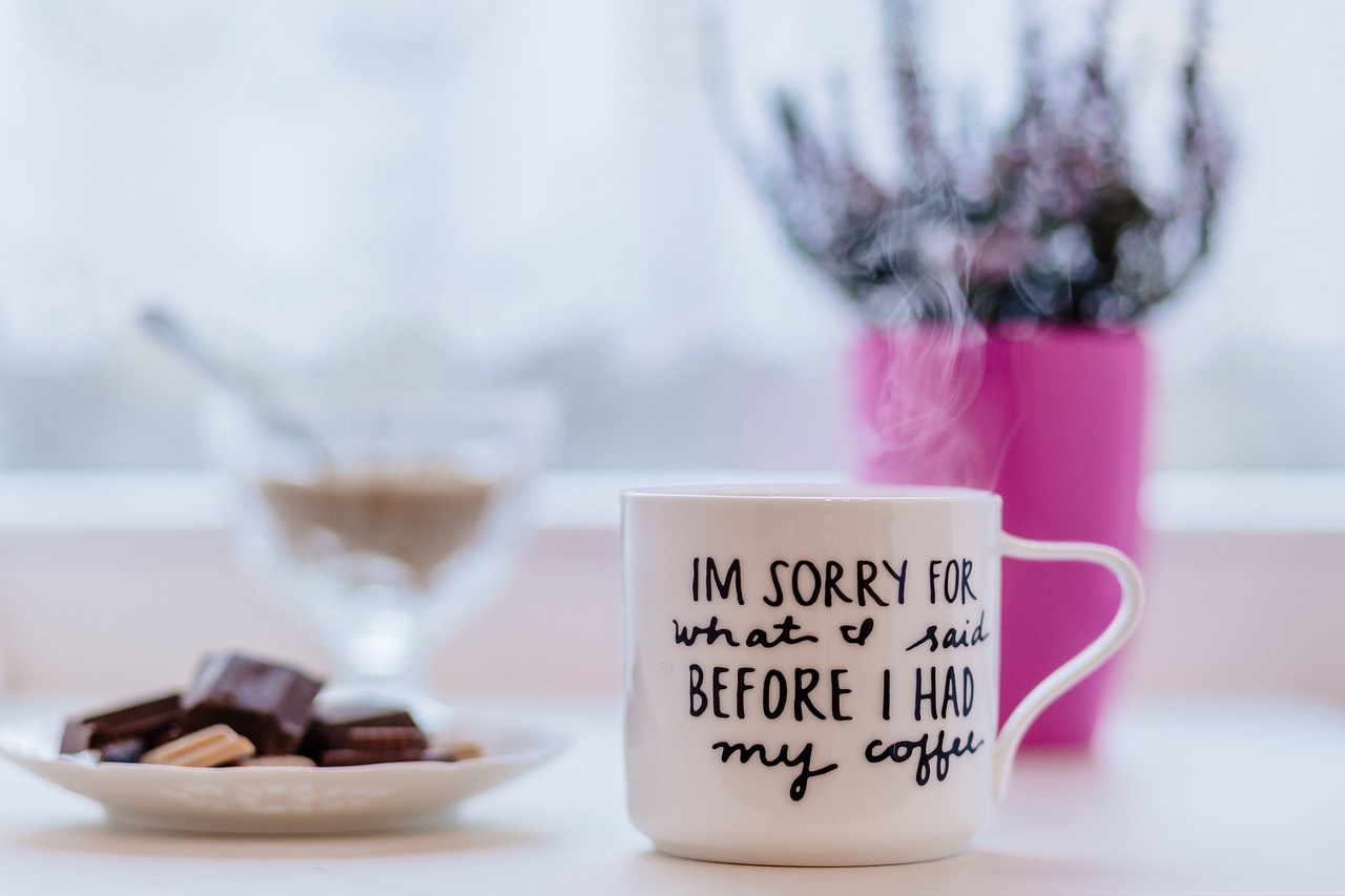 a coffee cup sitting on top of a table next to a plate of cookies, a picture, inspired by Jan Kupecký, shutterstock, happening, sarcastic, closeup photo, at home, stock photo