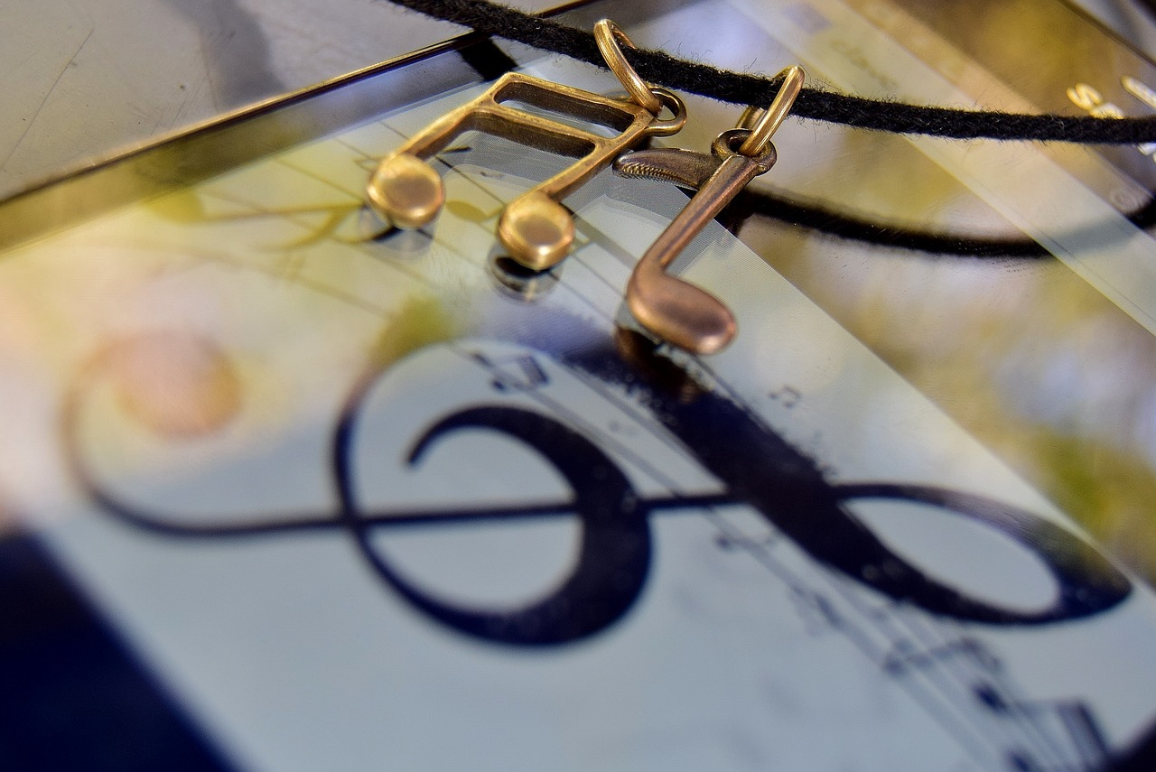 a close up of a clock with musical notes on it, a macro photograph, modernism, earings, brass plated, local close up, reflections in copper