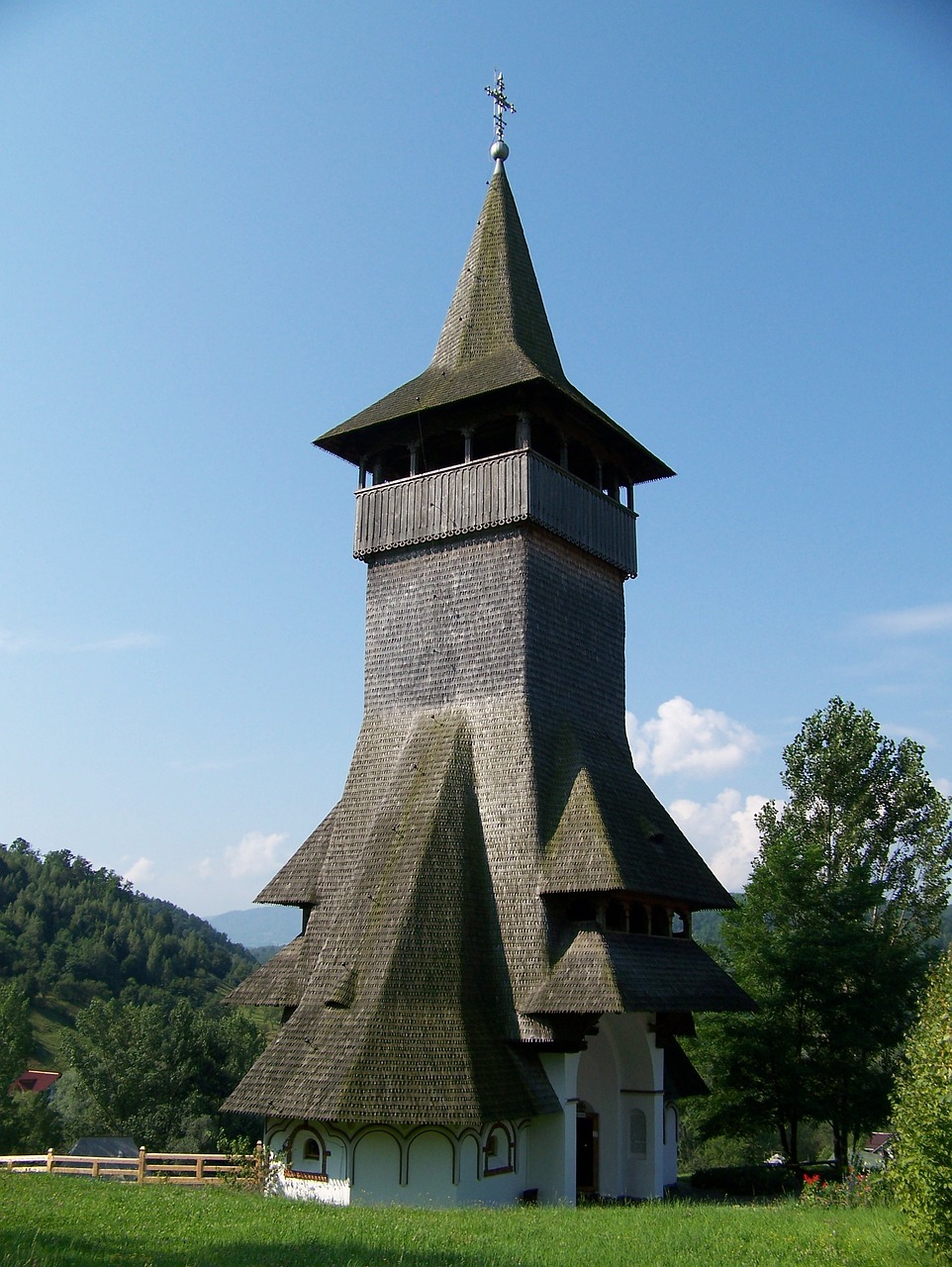 a church sitting in the middle of a lush green field, inspired by Hristofor Žefarović, flickr, renaissance, wooden structures, cone shaped, top - side view, integrated in the mountains