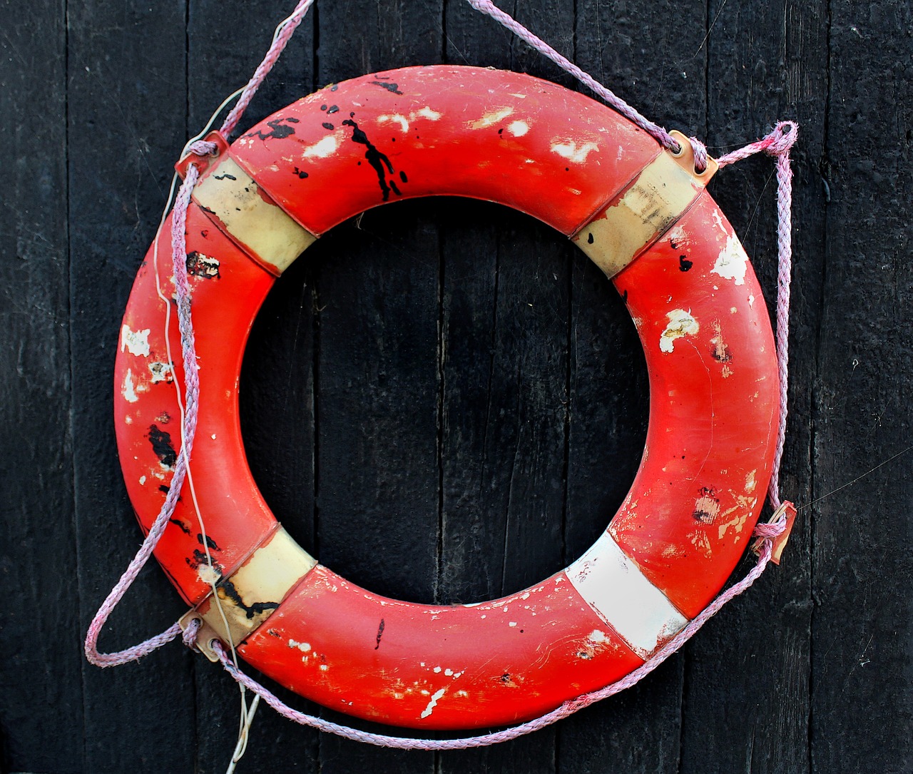 a life preserver hanging on a wooden wall, by Richard Carline, red and black colour scheme, high res photo, very round, battered