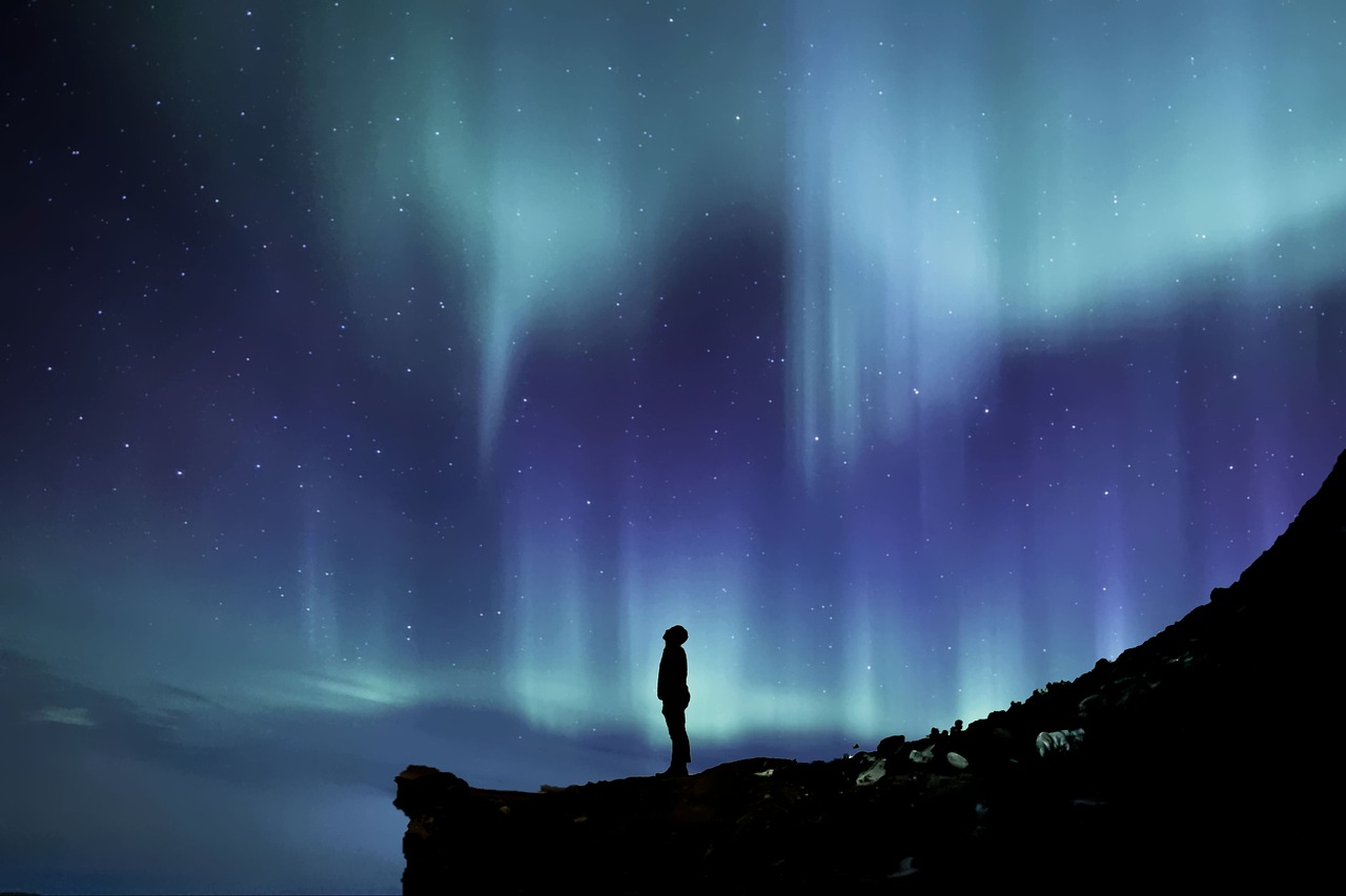 a person standing on a rock looking at the aurora bore, romanticism, istock, glowing blue, set photo, beautiful random images