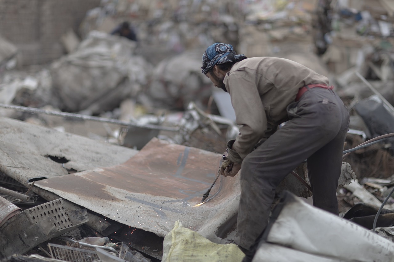 a man standing on top of a pile of rubble, a photo, welding torches for arms, close - up photo, cairo, iron cladding