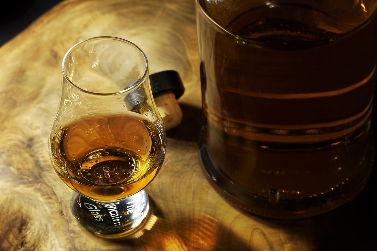 a glass of alcohol sitting on top of a wooden table, flickr, celtic, grain”, drinks bourbon, nice face