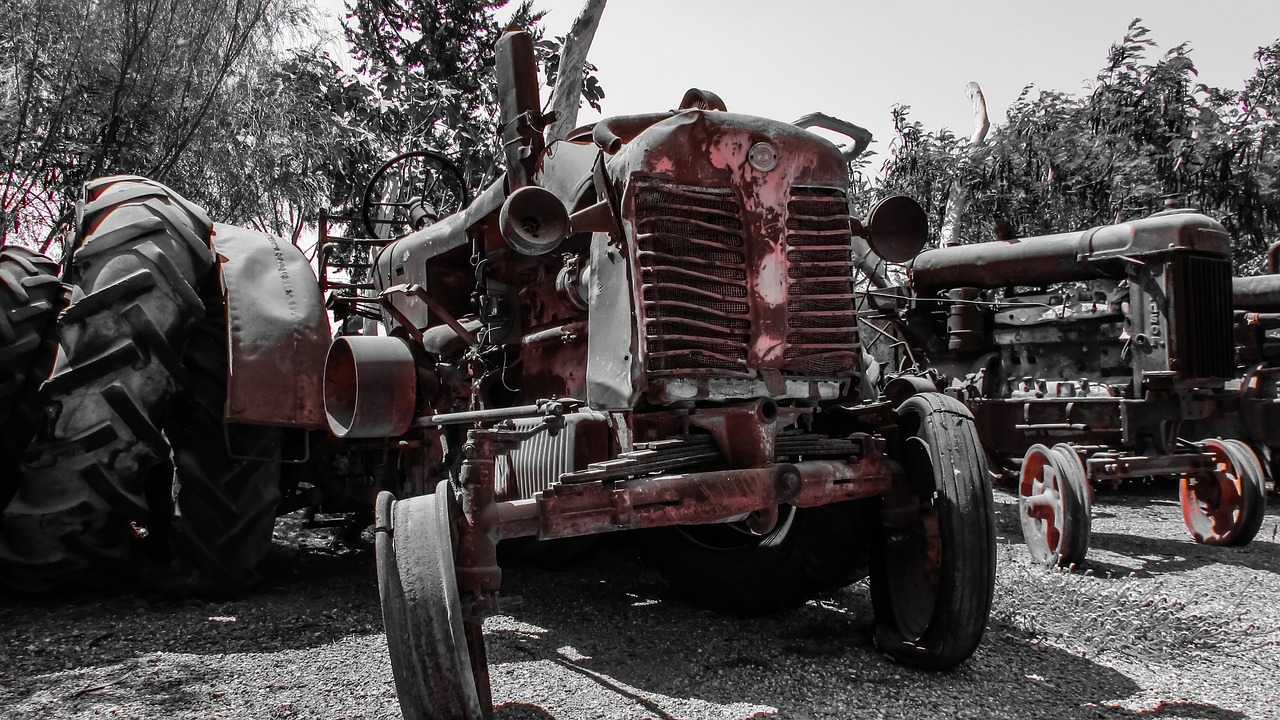 a black and white photo of an old tractor, auto-destructive art, color red, with damaged rusty arms, outdoor photo, shaded