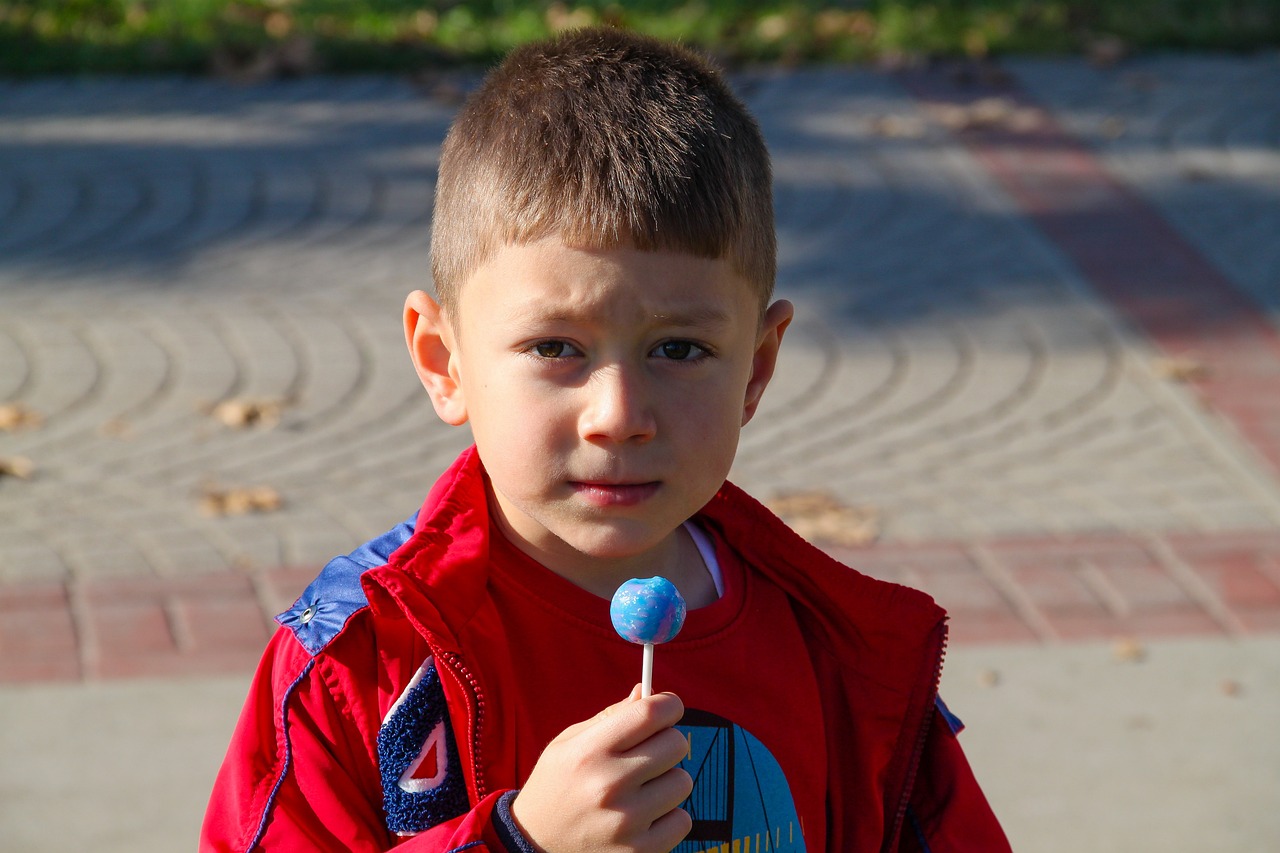 a young boy holding a lollipop in his hand, an indifferent face, outdoor photo, crying big blue tears, square