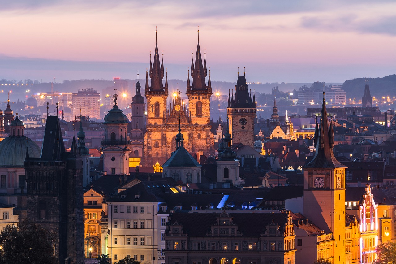 a view of a city at night from the top of a hill, by Matija Jama, shutterstock, baroque, majestic spires, lit in a dawn light, alabaster gothic cathedral, vibrant vivid colors