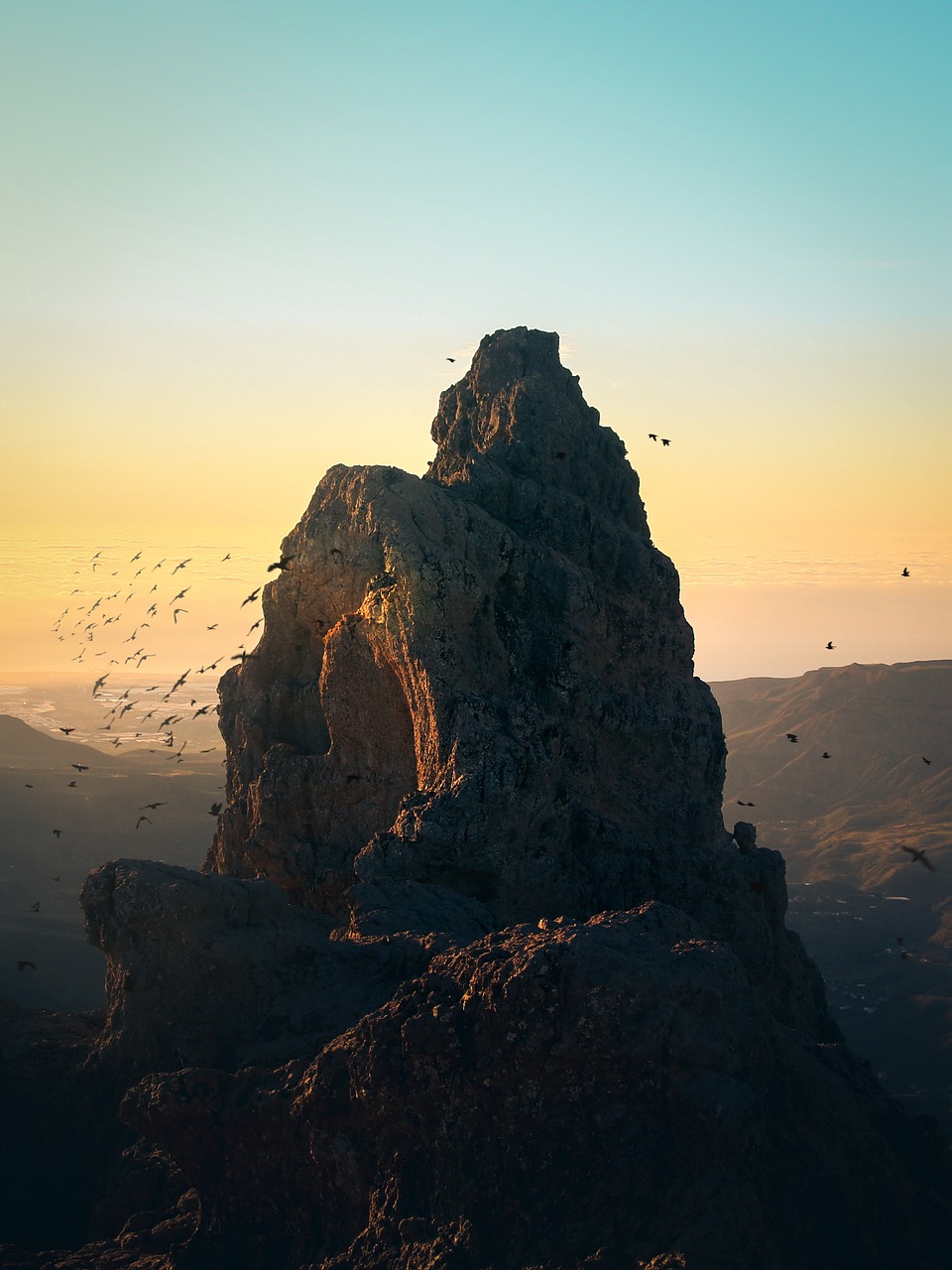 a large group of birds flying over a mountain, by Andrei Kolkoutine, romanticism, monolith, photography alexey gurylev, spire, warm sundown
