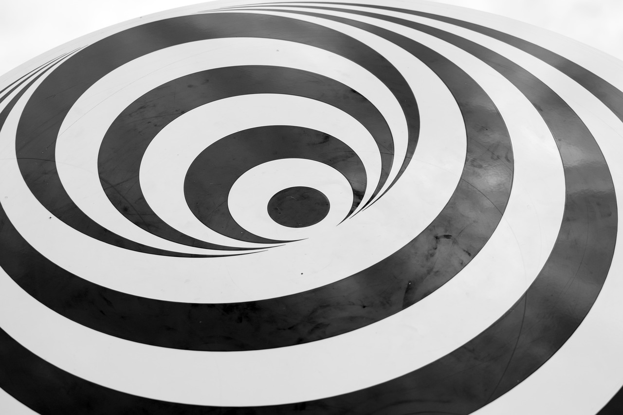 a black and white photo of a circular object, by Bridget Riley, unsplash, swirly body painting, 🦑 design, twilight zone background, vinyl