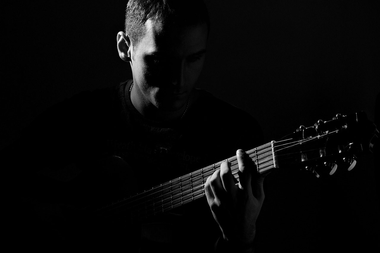 a man playing a guitar in the dark, a picture, by Eugeniusz Zak, minimalism, profile picture 1024px, looks sad and solemn, monochromatic photo, blog-photo