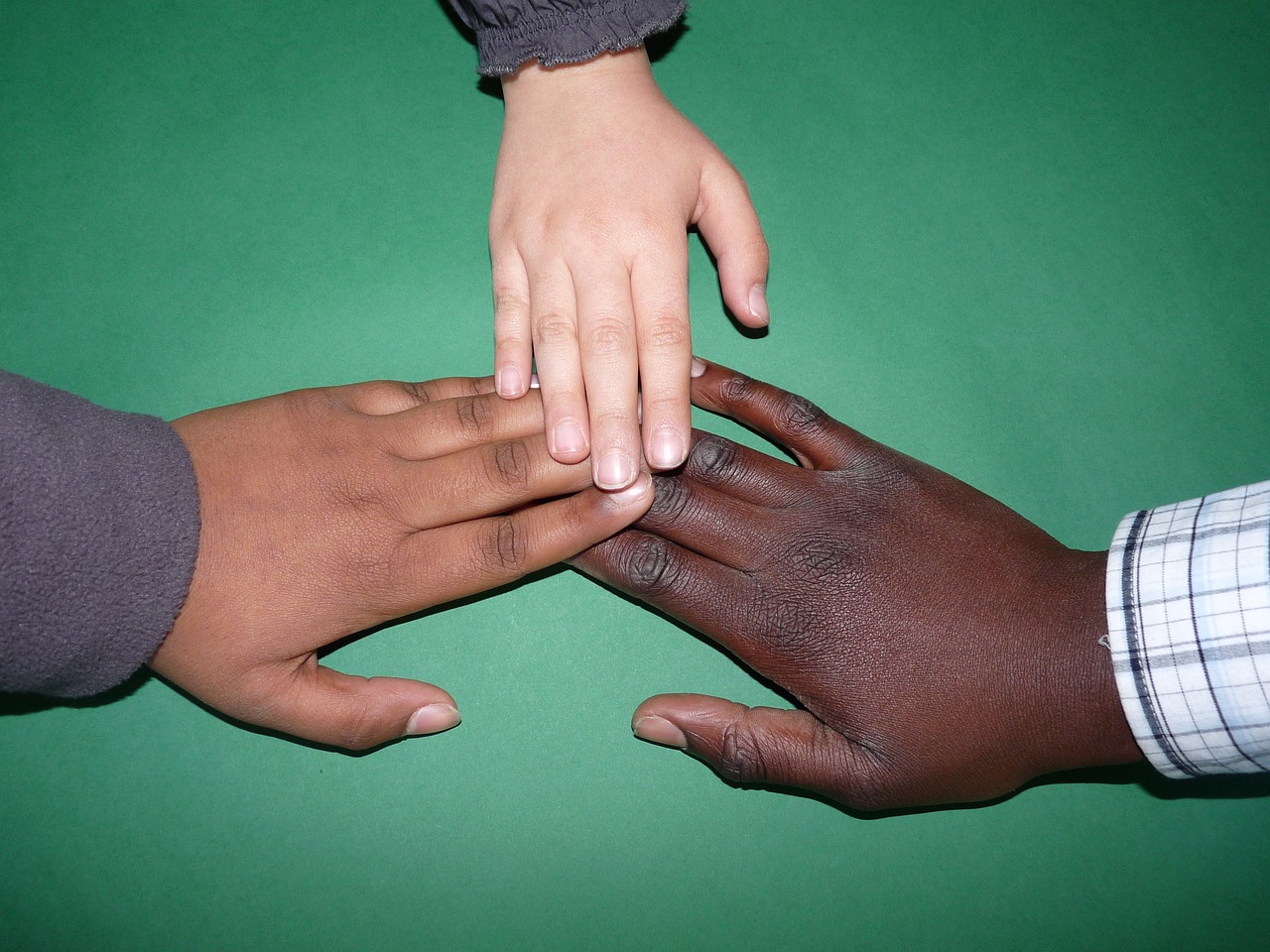 a group of people putting their hands together, by Susan Heidi, flickr, hurufiyya, dark brown white green colours, rule of third!!!!, black skin!!!, best friends