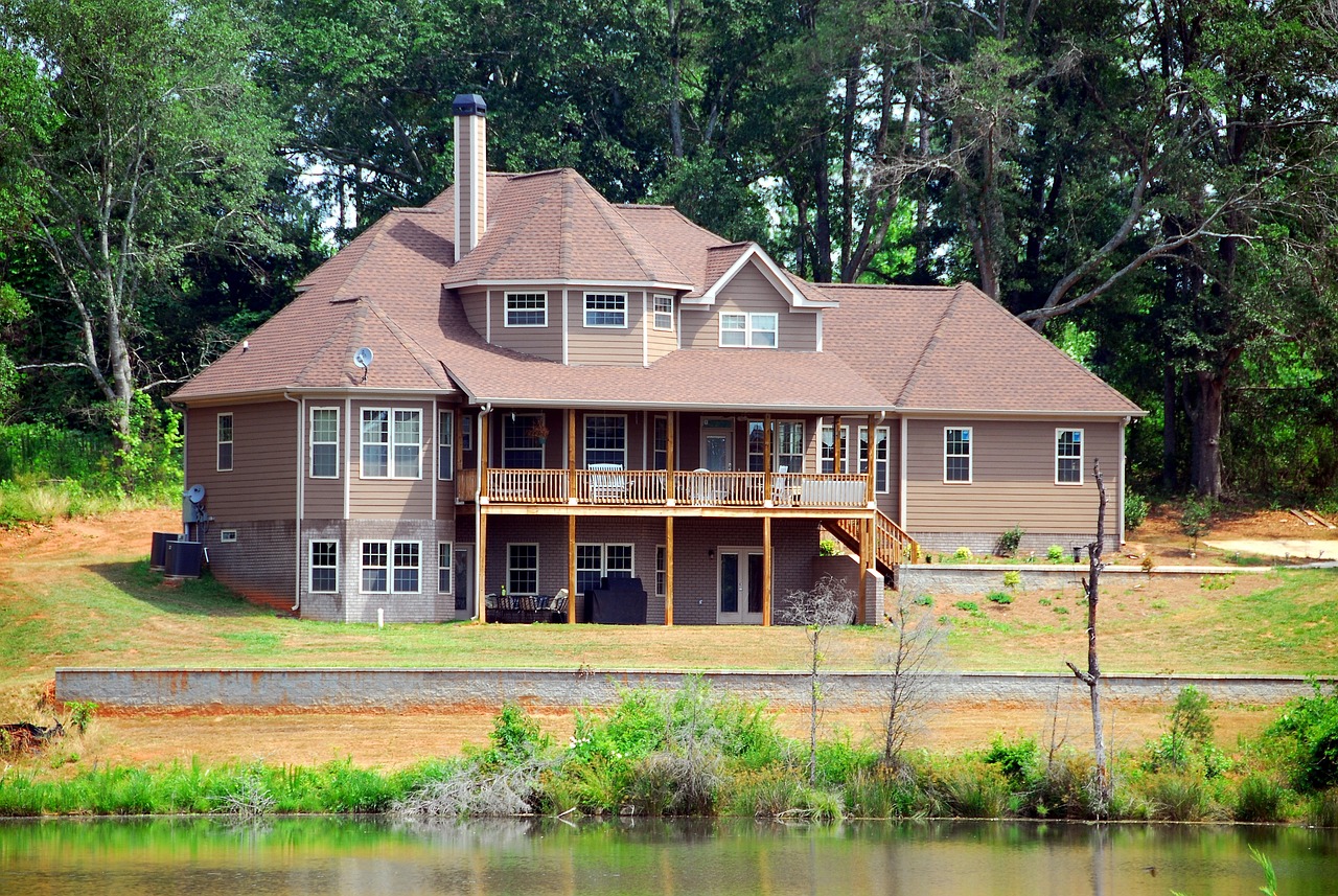 a house sitting on top of a lush green hillside, by Randy Post, shutterstock, lake house, 3 / 4 view from back, craftsman home, completely new