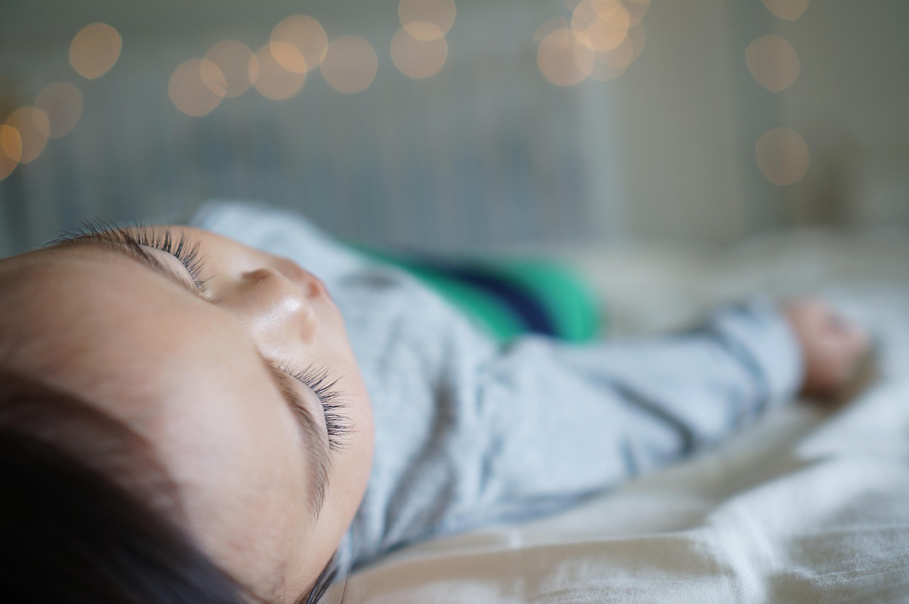a close up of a baby sleeping on a bed, a picture, bokeh top cinematic lighting, lights beaming out of eyes, profile image, forward facing