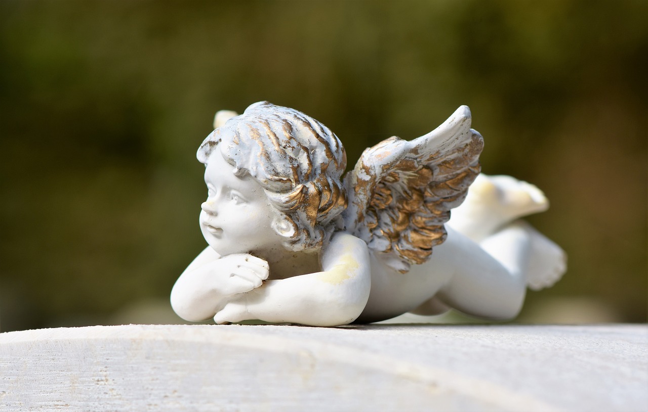 a close up of a statue of an angel, by Marie Angel, pixabay, figuration libre, laying back on a pillow, cute miniature resine figure, eye level view, cute decapodiformes