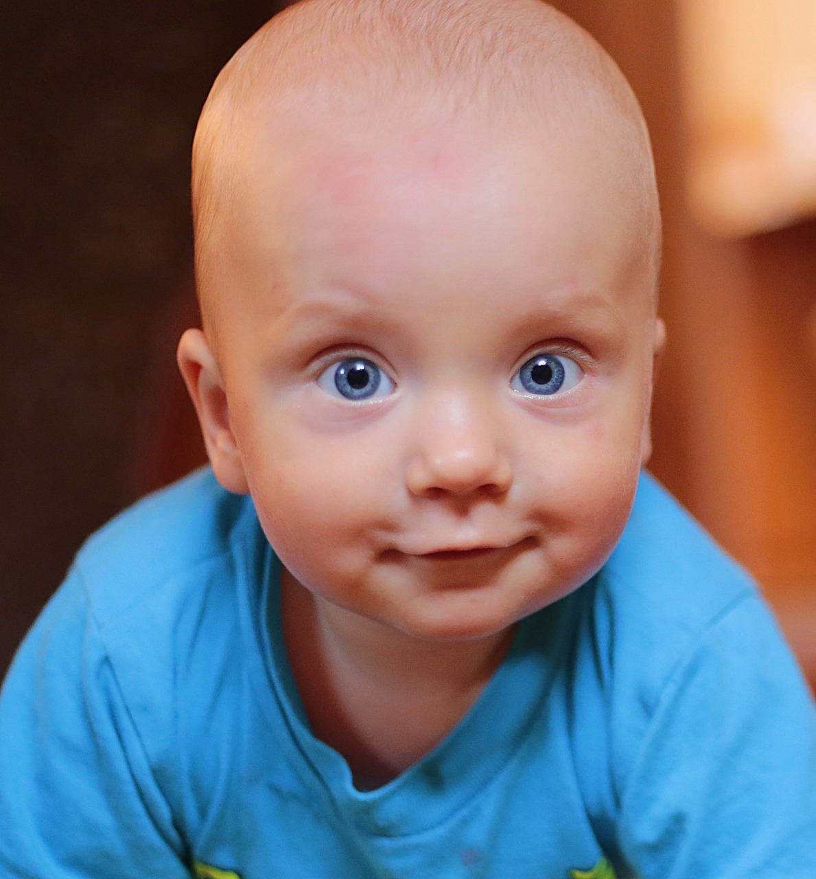 a close up of a baby wearing a blue shirt, a portrait, by Aleksander Gierymski, pexels, cute face big eyes and smiley, innocent look. rich vivid colors, ultrarealistic uhd faces, video