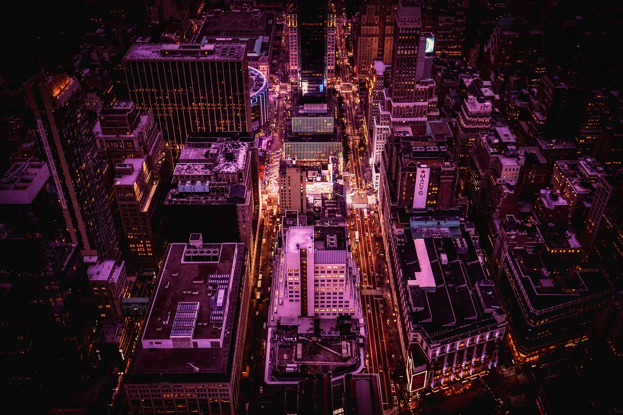 an aerial view of a city at night, by Dan Christensen, purple lighted street, new york buildings, post processed, cinematic shot!