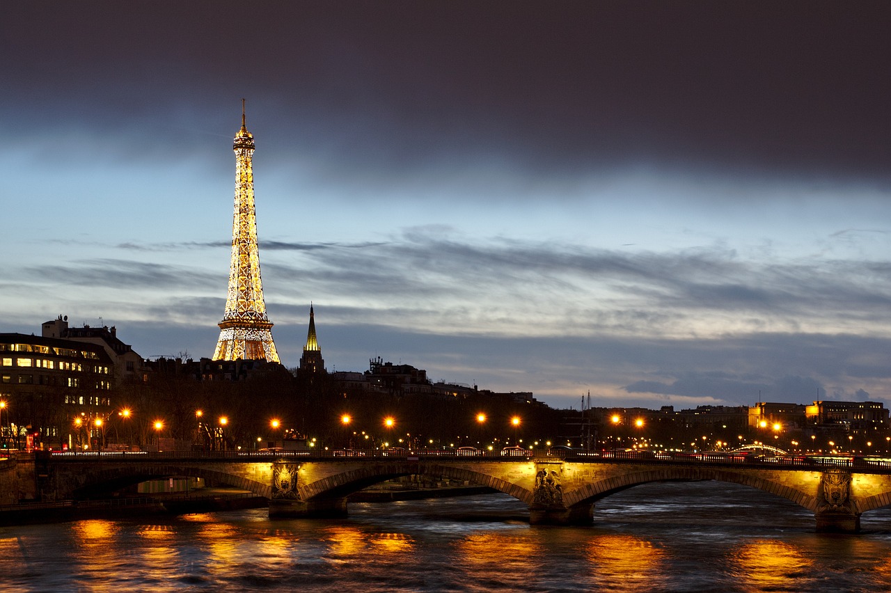 the eiffel tower is lit up at night, a picture, by Etienne Delessert, shutterstock, romanticism, river gorgeous lighting, istockphoto, bridge, stacked image