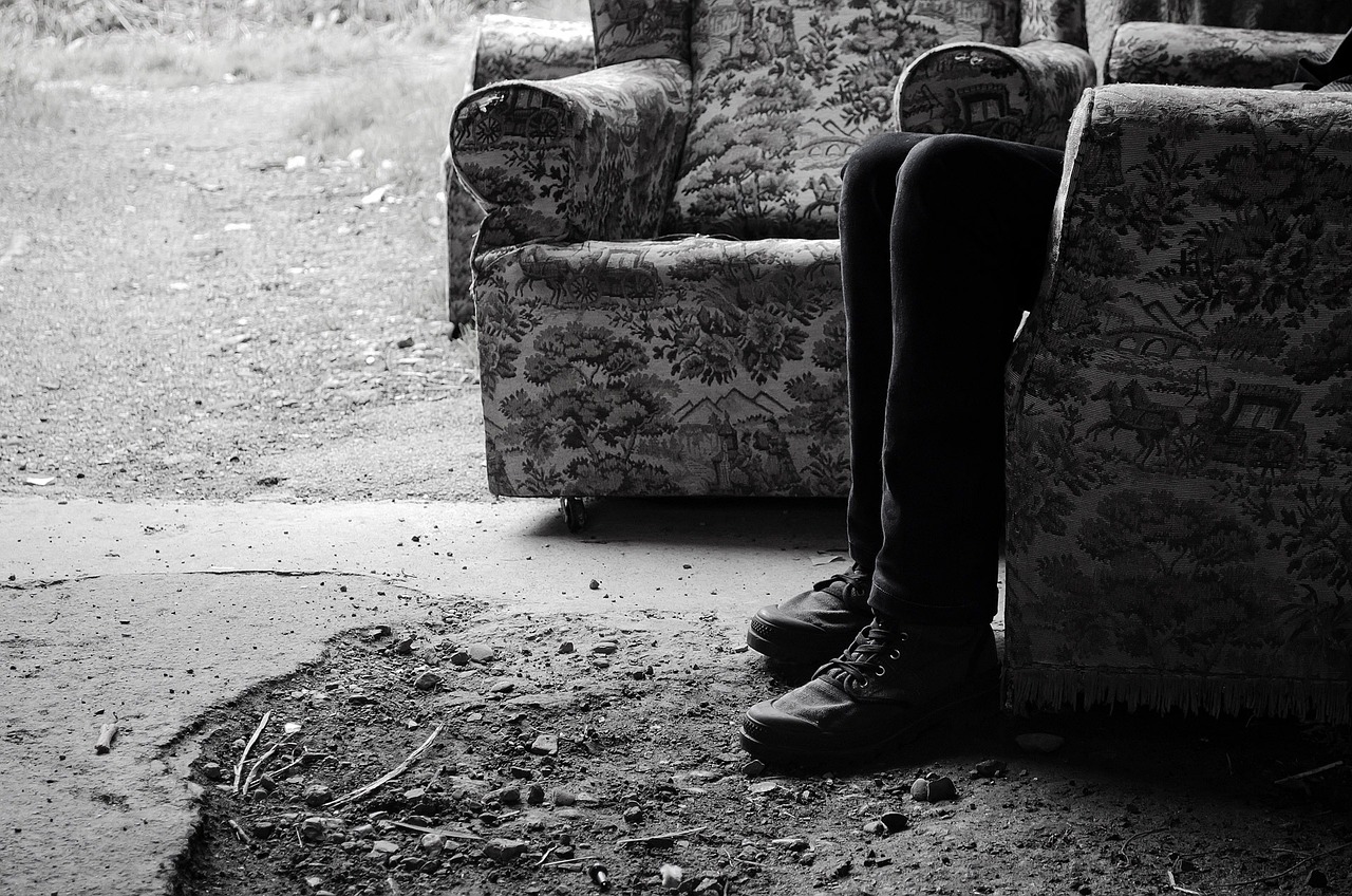 a black and white photo of a person sitting on a couch, pexels, realism, dilapidated, destroy lonely, sitting on the ground, absent friends