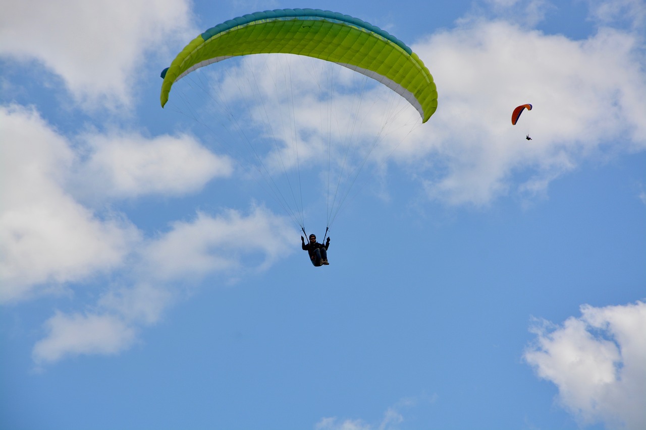 a person that is in the air with a parachute, a photo, green and blue colors, albuquerque, bright summer day, photo taken on a nikon