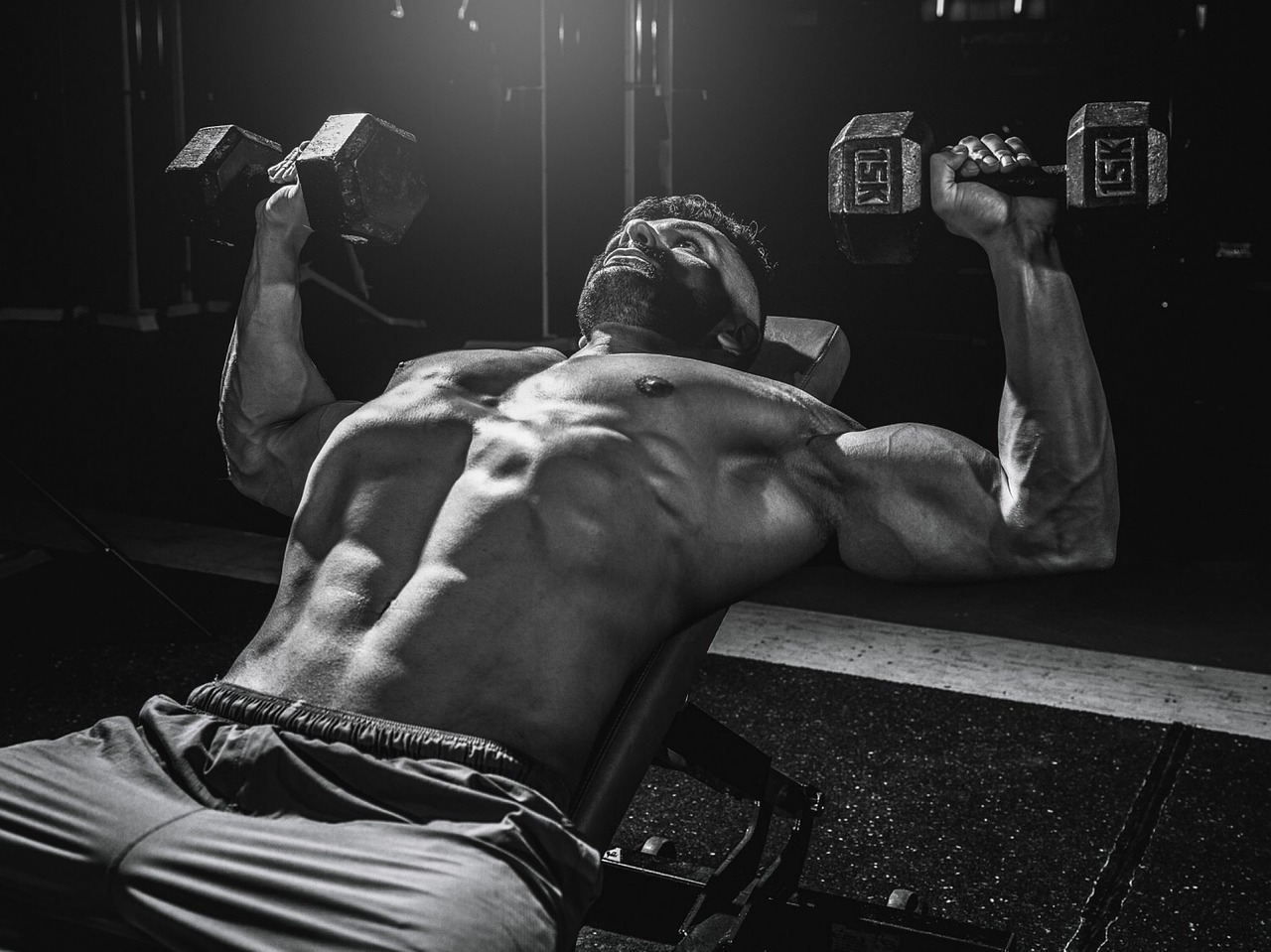 a black and white photo of a man lifting two dumbbells, by Etienne Delessert, dramatic cinematic action shot, resting on chest, bearded and built, clayton crain