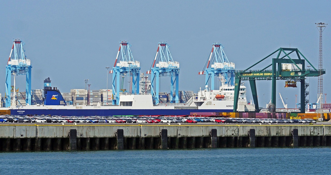 a large cargo ship sitting on top of a body of water, a photo, shutterstock, figuration libre, huge machine cranes, viewed from the harbor, wikimedia commons, three masts