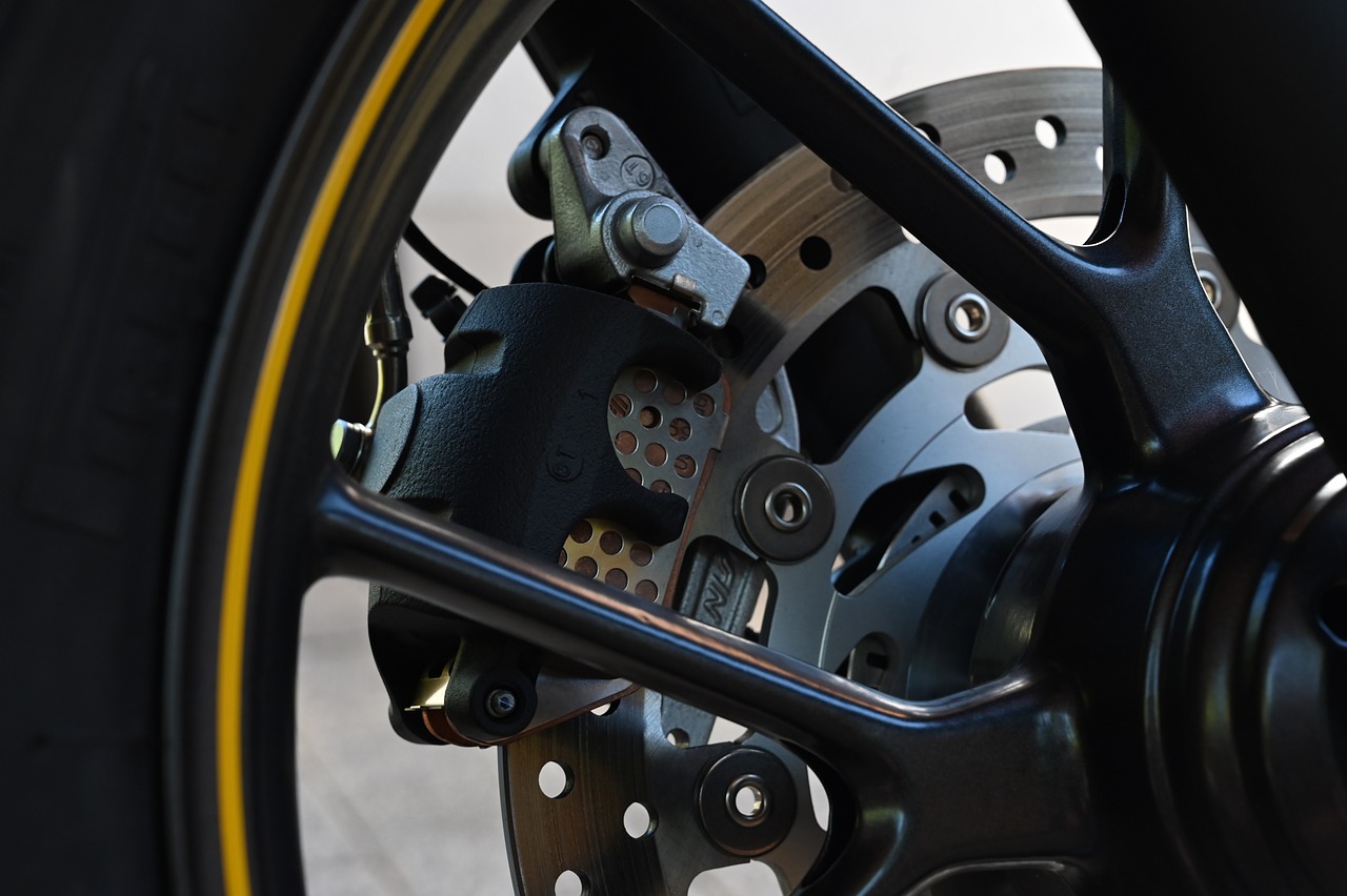 a close up of the front wheel of a motorcycle, black armor with yellow accents, photo taken from behind, levers, broken parts