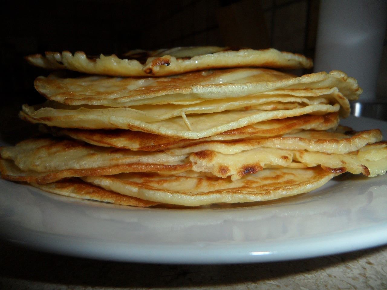 a stack of pancakes sitting on top of a white plate, by Aleksander Gierymski, flickr, renaissance, ethiopian, closeup - view, folded, stroopwaffel