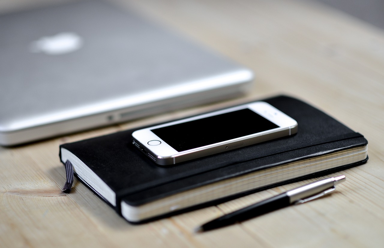 a cell phone sitting on top of a book next to a laptop, a sketch, pexels, white and black, silver accessories, sharp focused, tools