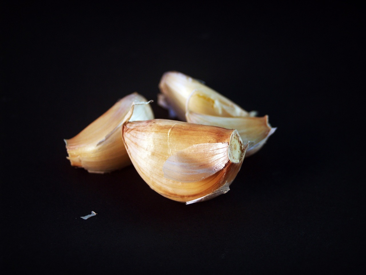 a couple of cloves of garlic on a black surface, a macro photograph, by Tom Carapic, miniature product photo, high detail product photo, chicken, productphoto