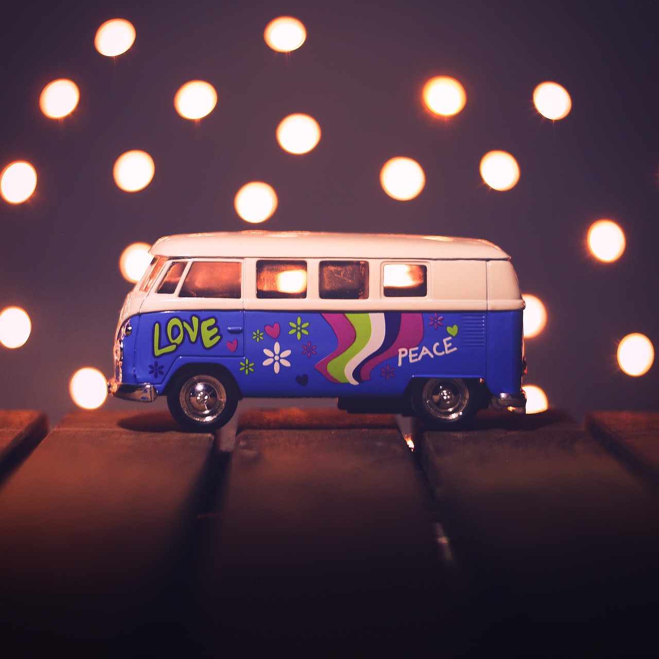 a toy van sitting on top of a wooden table, inspired by Chris LaBrooy, unsplash, graffiti, love peace and unity, shot at night with studio lights, 1960s flower power hippy, octane render ] ”