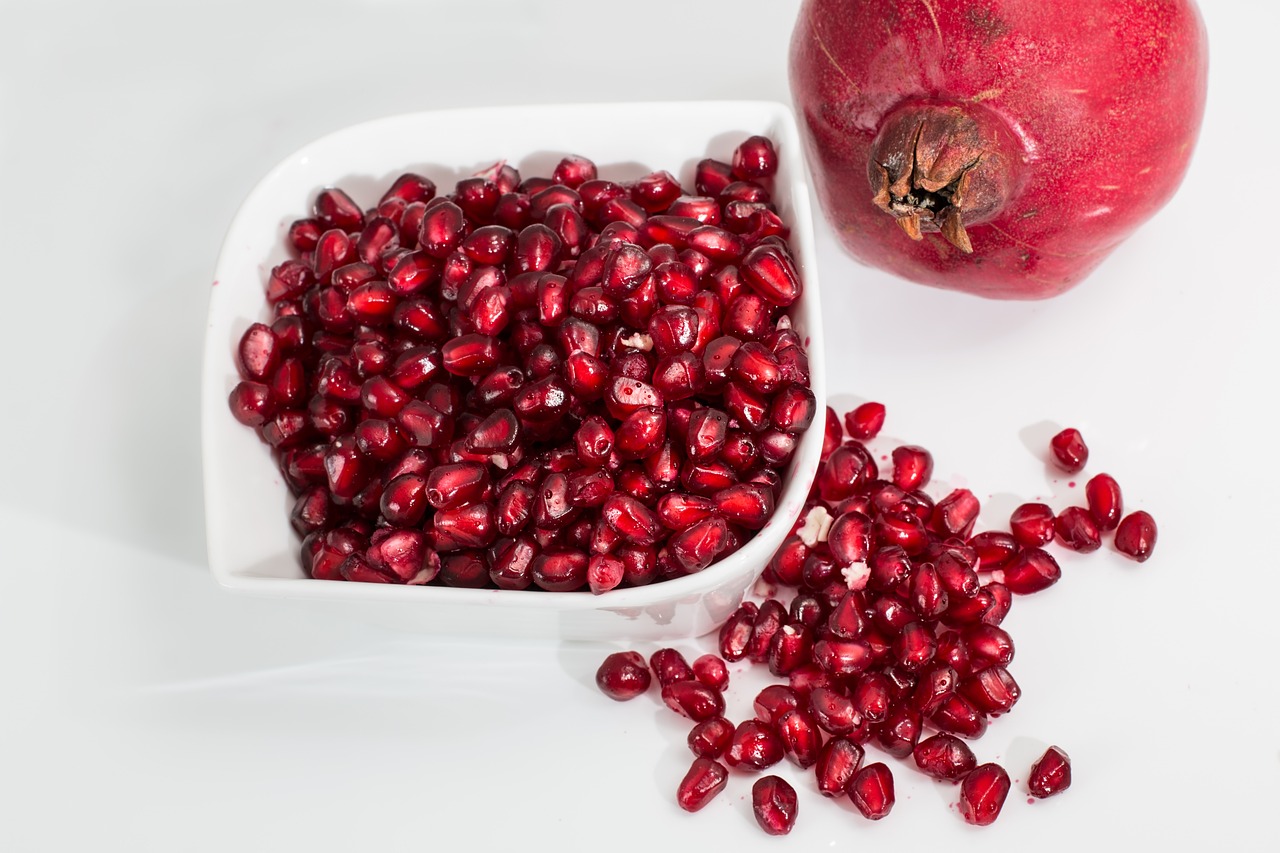 a bowl of pomegranate next to a pomegranate, product introduction photo, productphoto