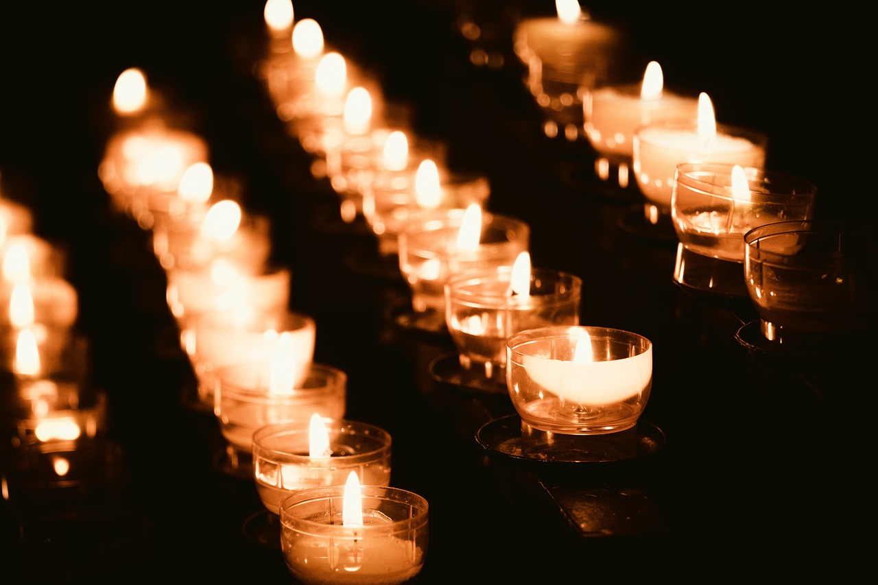 a row of lit candles sitting on top of a table, a photo, by Bernard Meninsky, pexels, ossuary, stock photo, lines of lights, many details