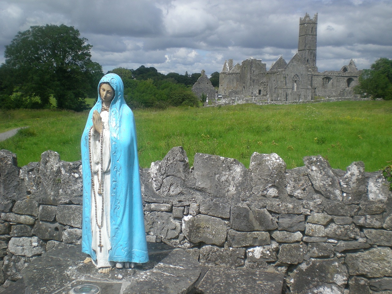a statue of a person wearing a blue robe, a statue, by Edward Corbett, flickr, old abbey in the background, virgin mary, mayo, mother theresa