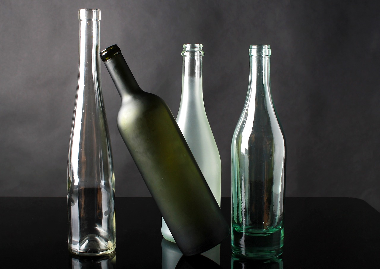 three empty bottles sitting next to each other on a table, a picture, by Emanuel de Witte, pixabay, on a gray background, dark green glass, detailed product photo, four