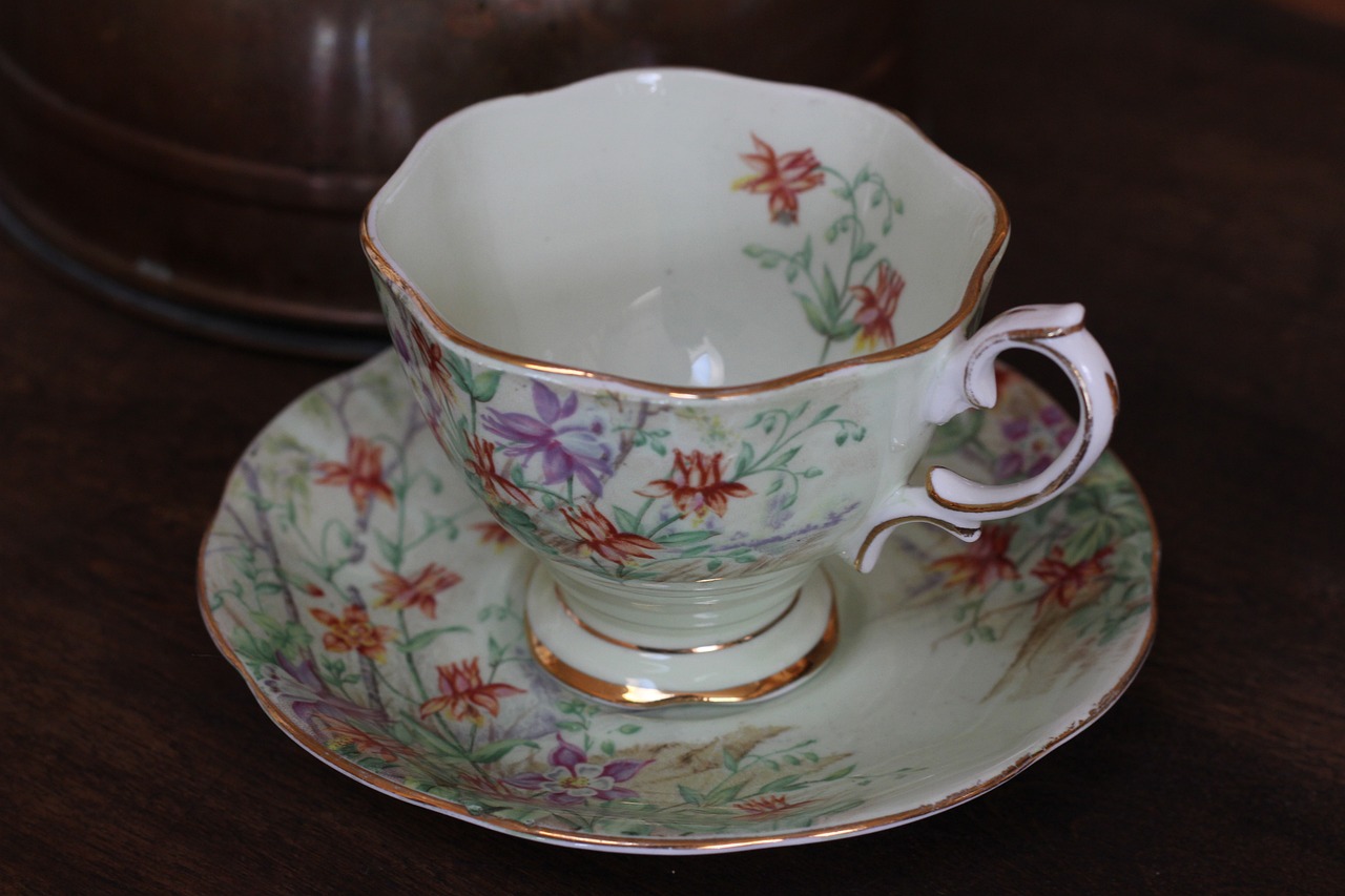 a close up of a cup and saucer on a table, by Cicely Hey, australian wildflowers, antique piece, display item, green