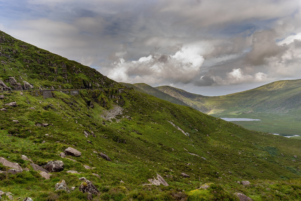 a herd of sheep standing on top of a lush green hillside, by Bedwyr Williams, flickr, a lake between mountains, mayo, iso 1 0 0 wide view, distant clouds