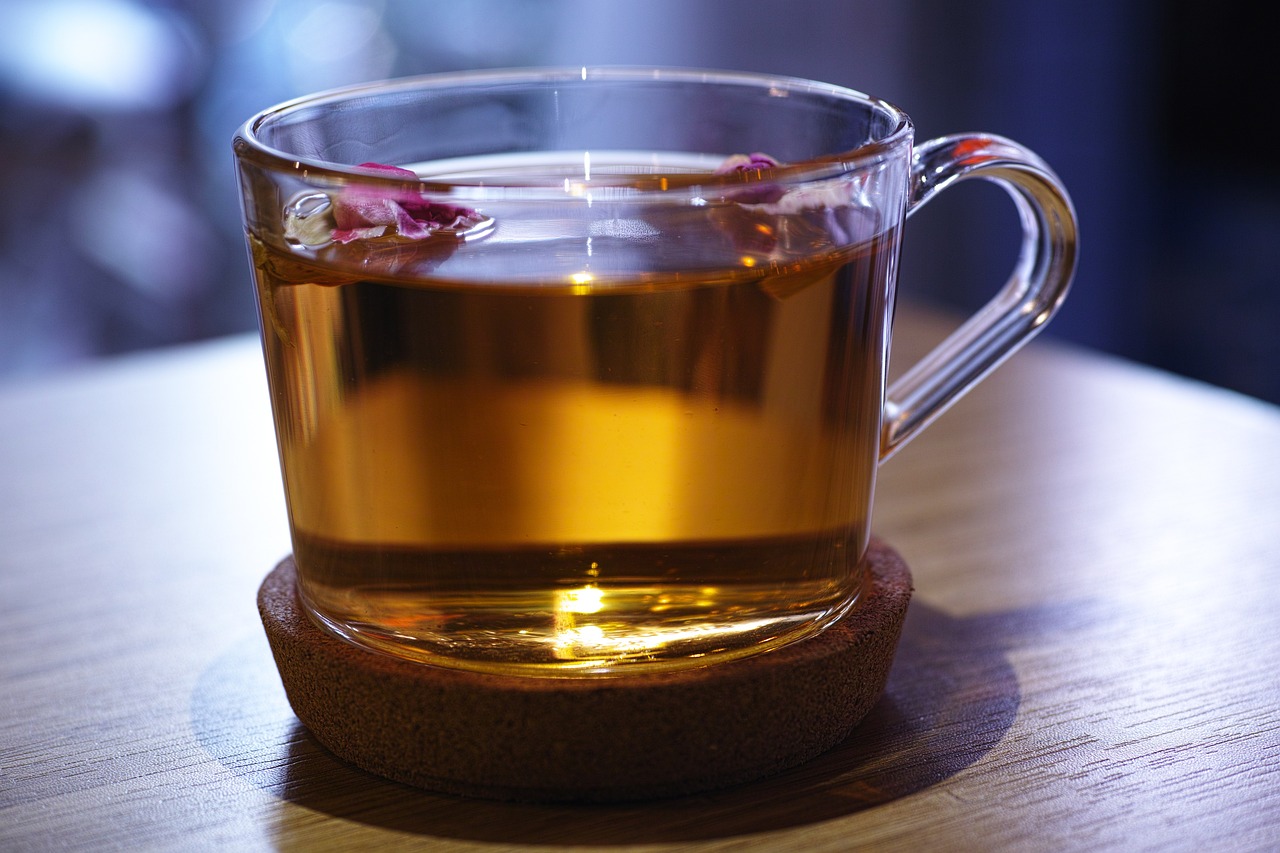 a cup of tea sitting on top of a wooden table, pexels, renaissance, glass, deep detailed, aspic, lit from the side