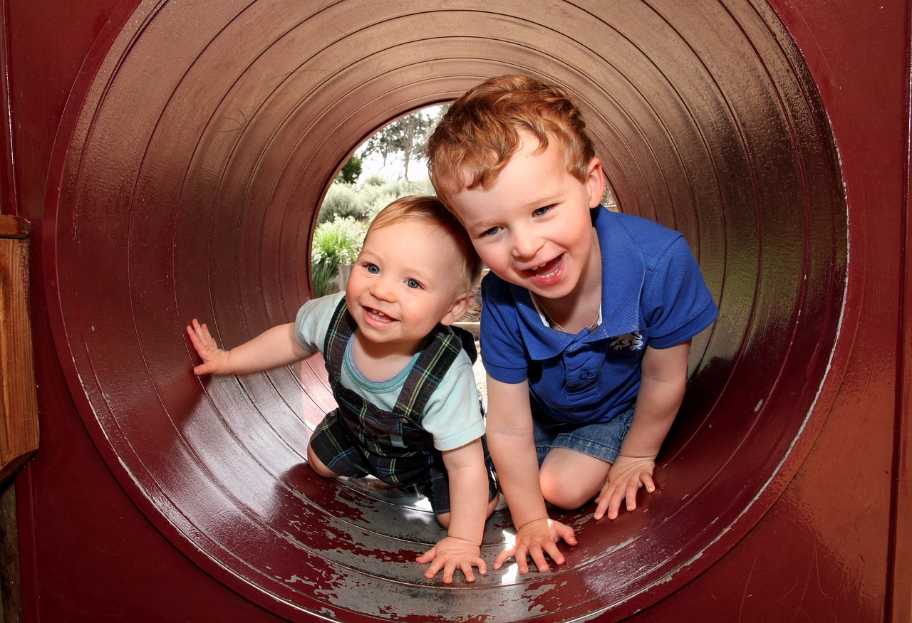 a couple of kids that are inside of a tube, by Matt Stewart, pixabay, huge black round hole, toddler, both smiling for the camera, stock photo