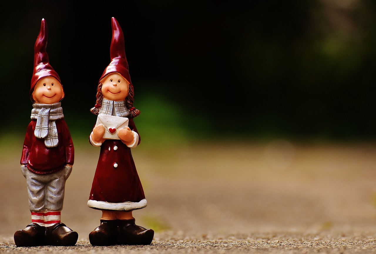 a couple of figurines standing next to each other, a picture, by Jesper Knudsen, pexels, folk art, little elf girl, maroon and white, dunce, santa