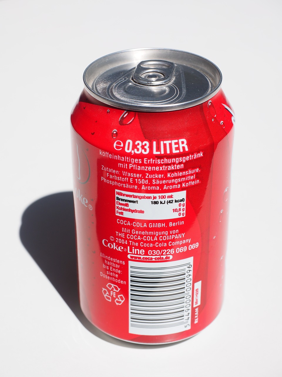 a can of soda sitting on top of a table, by Oskar Lüthy, high detailed photography red, dezeen, litter, product label