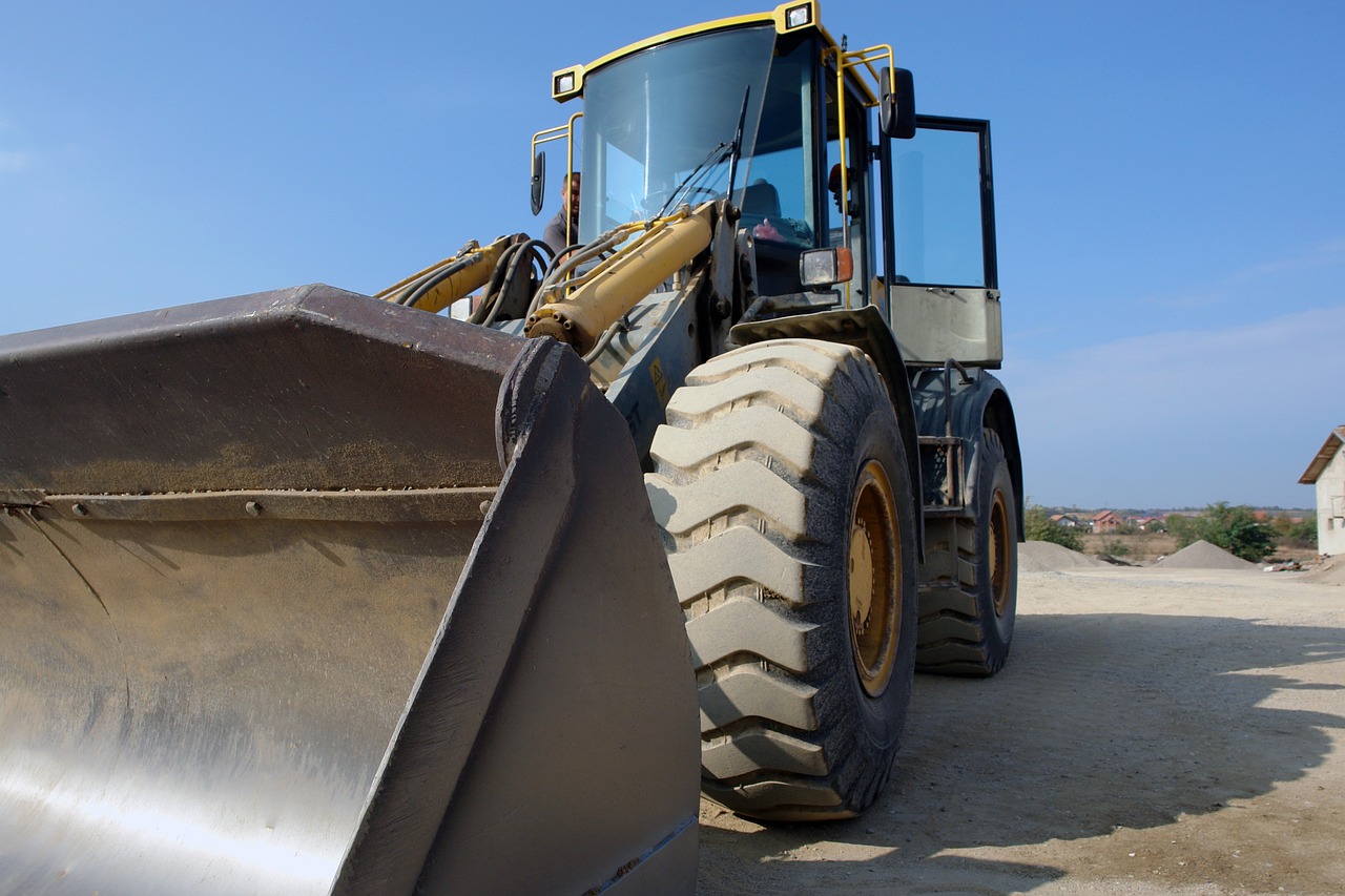 a large wheel loader sitting on top of a dirt field, a photo, by Steven Belledin, figuration libre, pristine and clean design, about to step on you, correct details, detaild