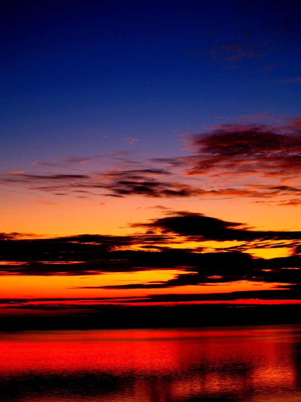 a plane flying over a body of water at sunset, a photo, by Andrei Kolkoutine, romanticism, colorful night sky, sunset clouds, deep colours. ”, break of dawn on venus