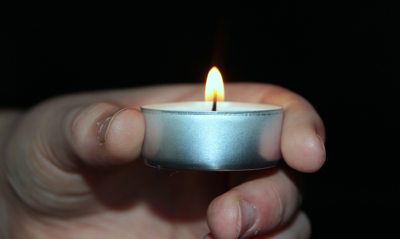 a person holding a lit candle in their hand, a picture, by Jan Rustem, hurufiyya, awareness, shiny silver, wikimedia, small fire