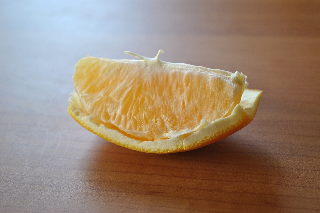 a half orange sitting on top of a wooden table, flickr, amogus photo - realistic, it has lemon skin texture, shredded, only a mouth with long