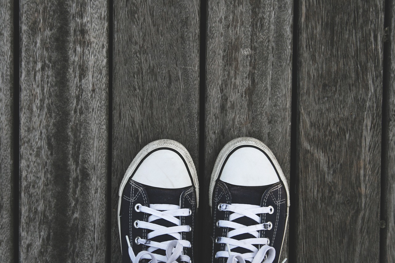 a pair of black sneakers sitting on top of a wooden floor, pexels, white and black color palette, 400 steps, converse, deck