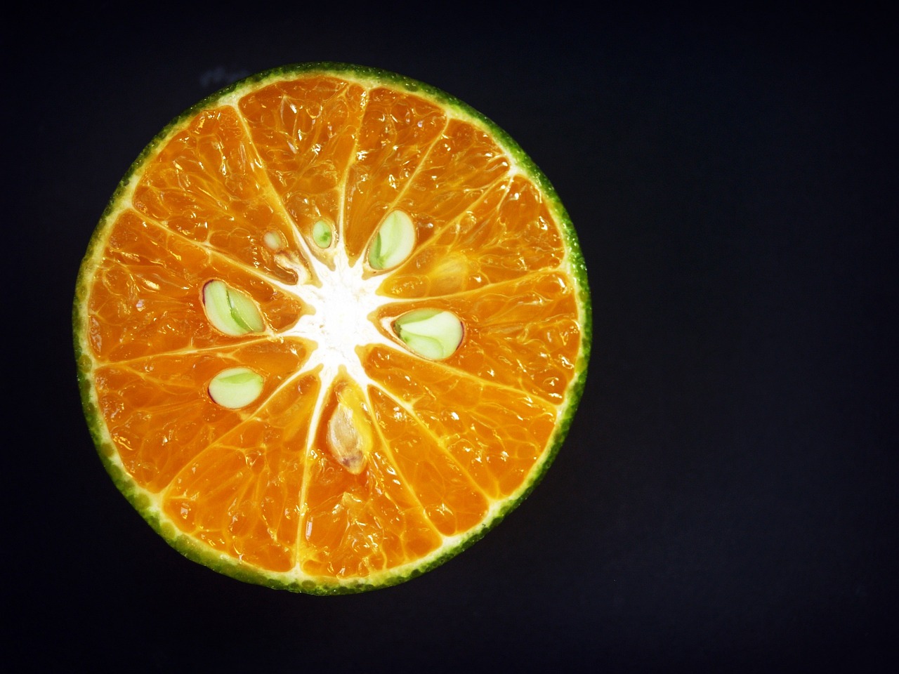 an orange cut in half on a black surface, by Jan Rustem, pexels, bright green dark orange, view from below, lime, citrinitas